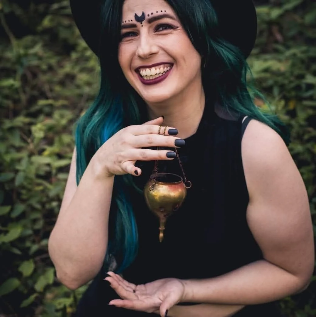 Alannah smiling in a witch hat with long teal hair